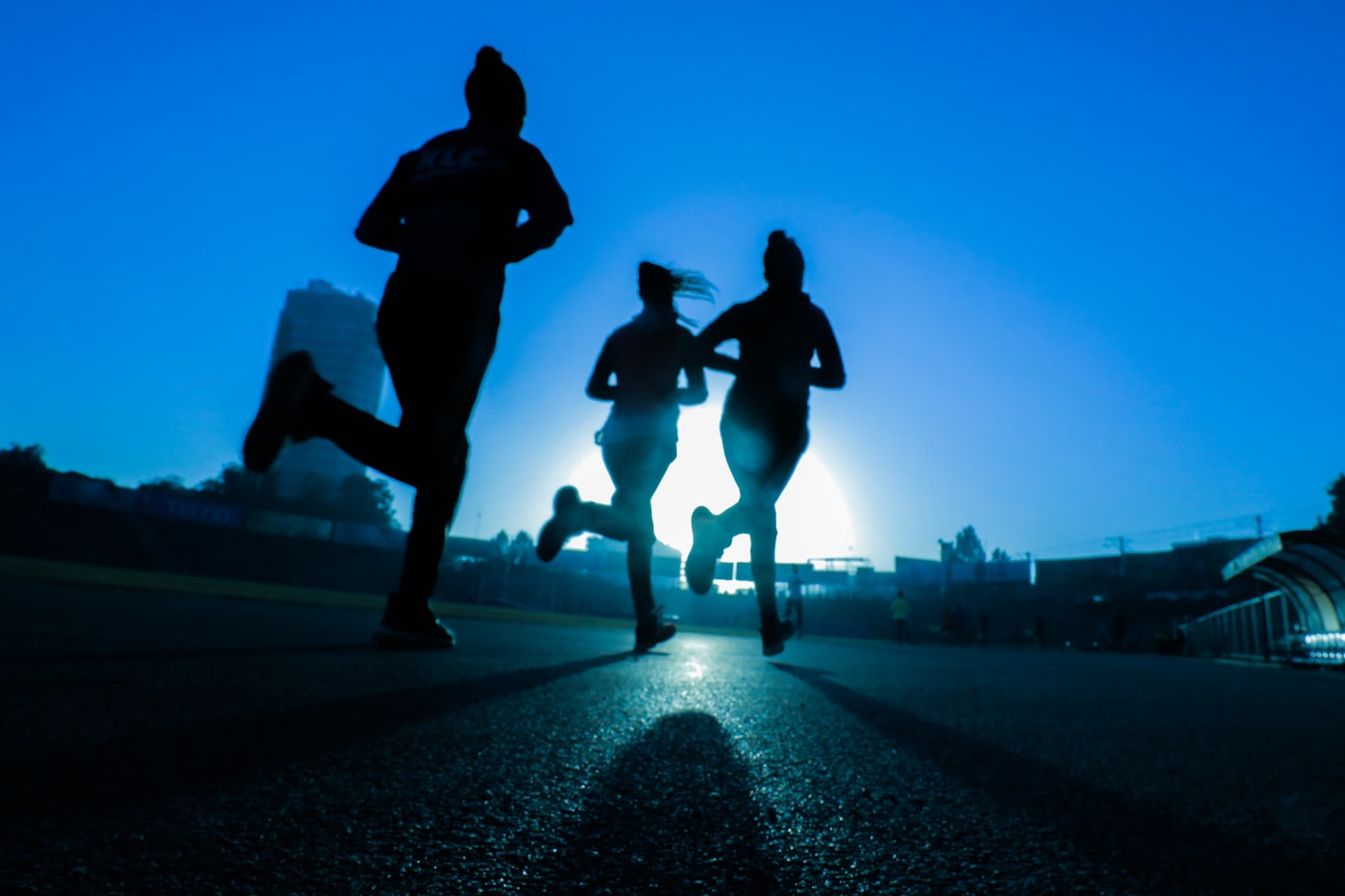 Runners in silhouette on a track at dusk
